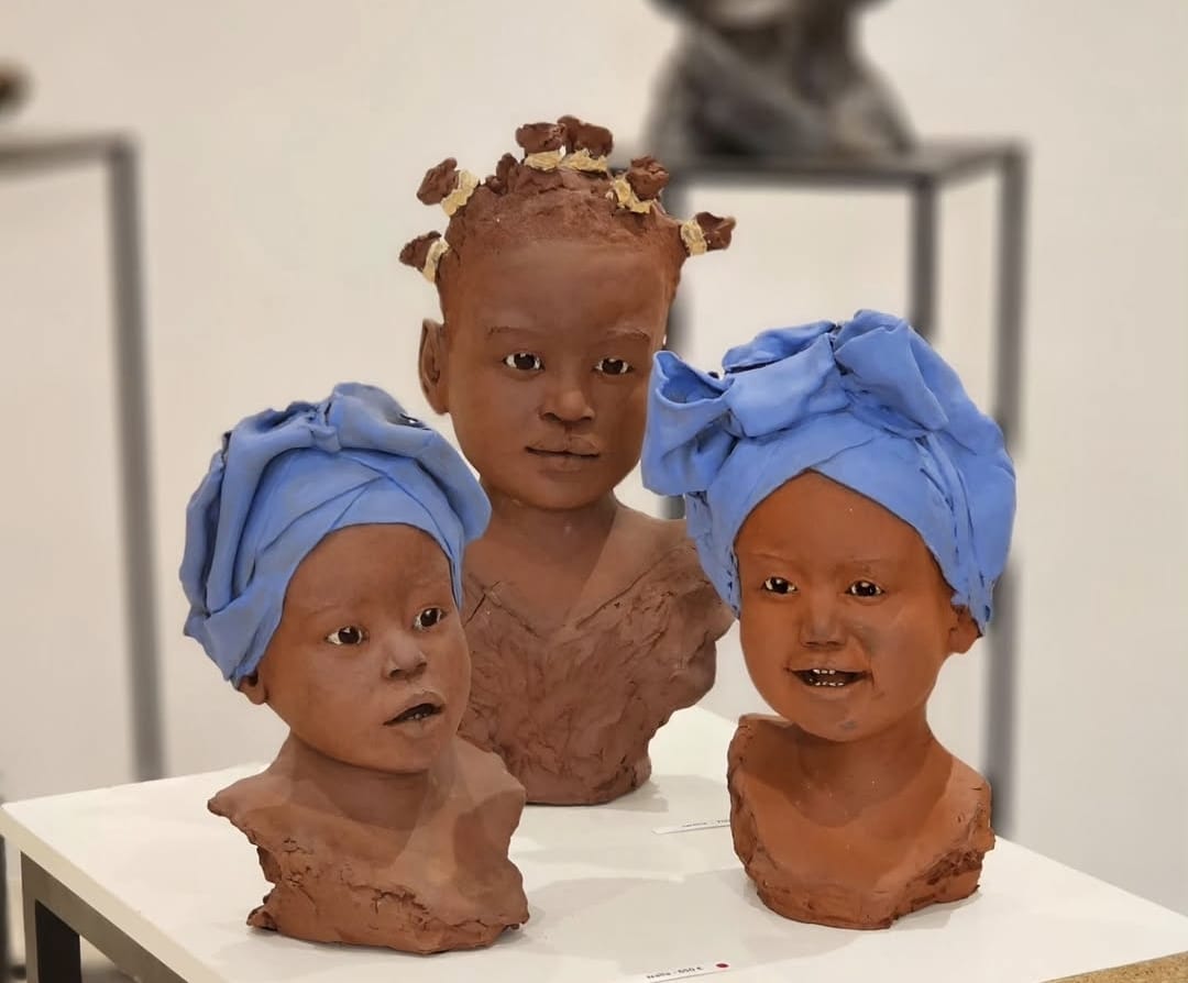 Three children busts — terracotta with blue headwraps